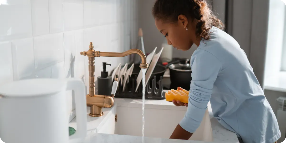 Girl washing dishes at the kitchen sink