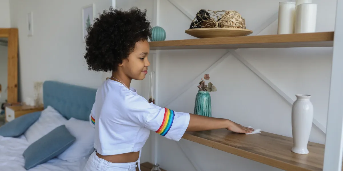 Girl tidying her bedroom by organising items on a shelf