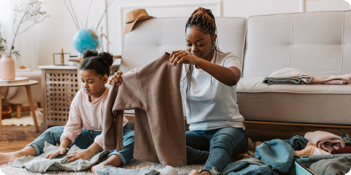 Two children folding laundry together on the couch