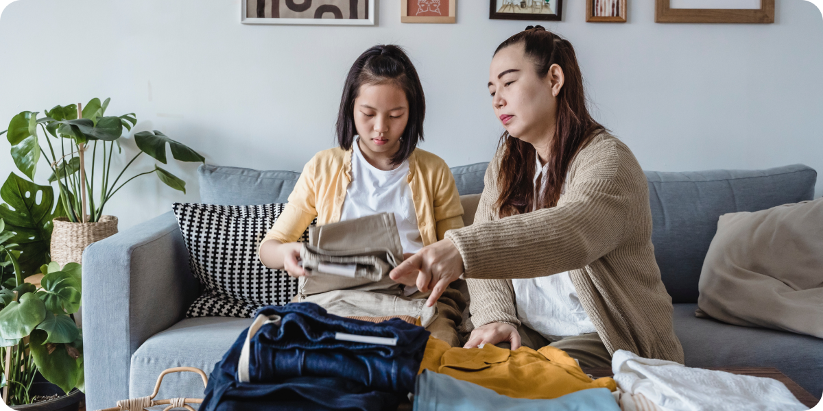 Two people sorting and folding clothes on a couch